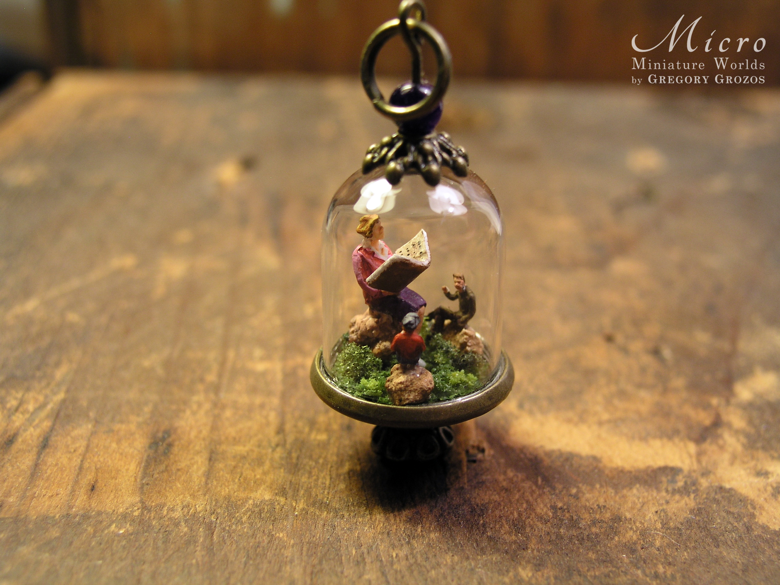 Miniature World pendant. A giant woman is reading stories to two tiny people