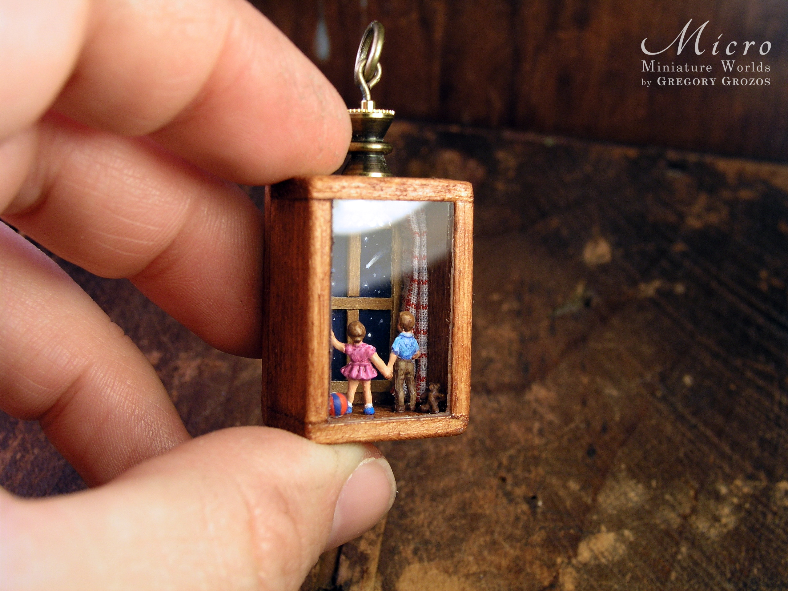 Miniature World Pendant. A boy and birl are holding hands while looking out a window at the night sky.