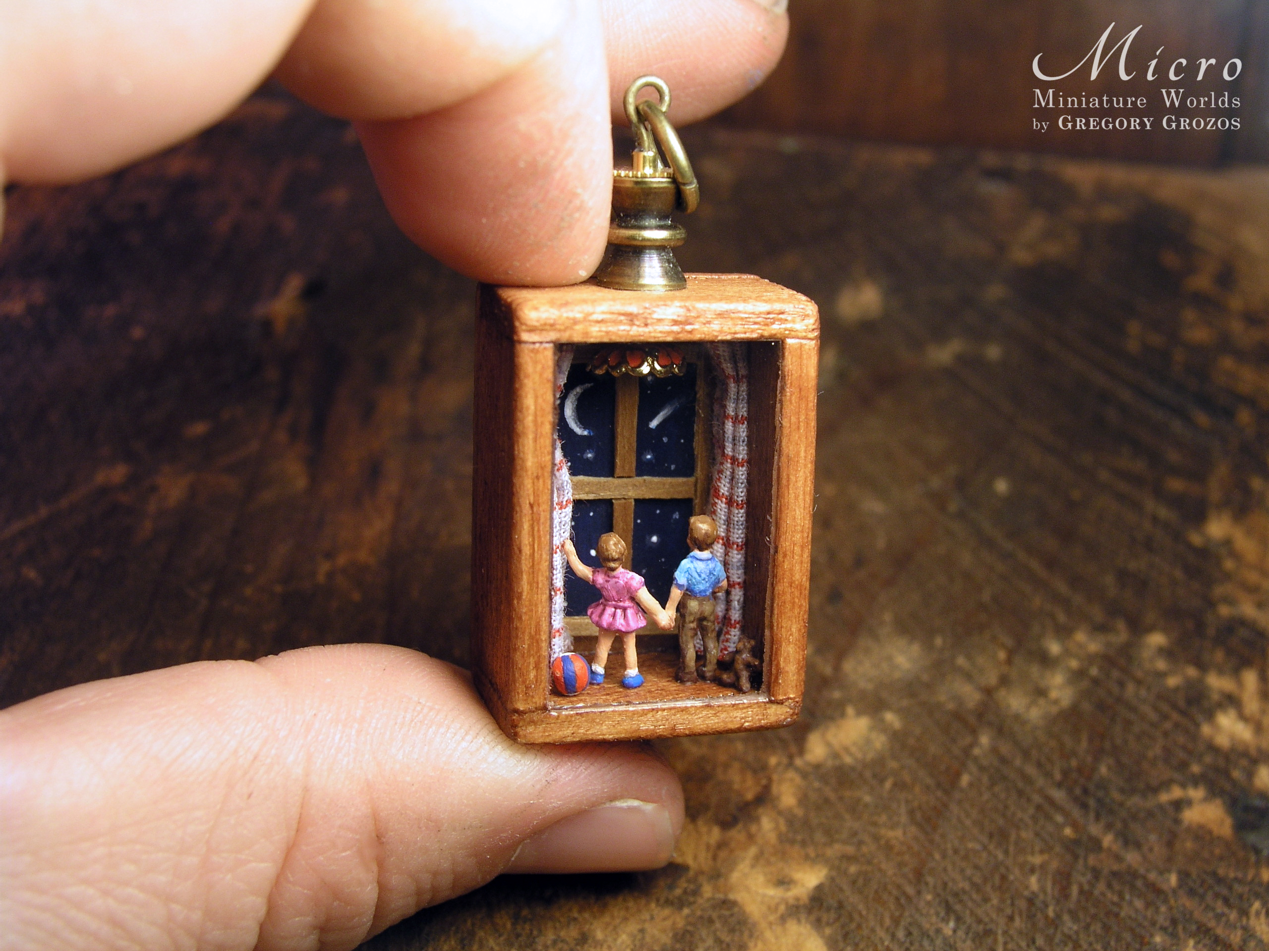 Miniature World Pendant. A boy and birl are holding hands while looking out a window at the night sky.