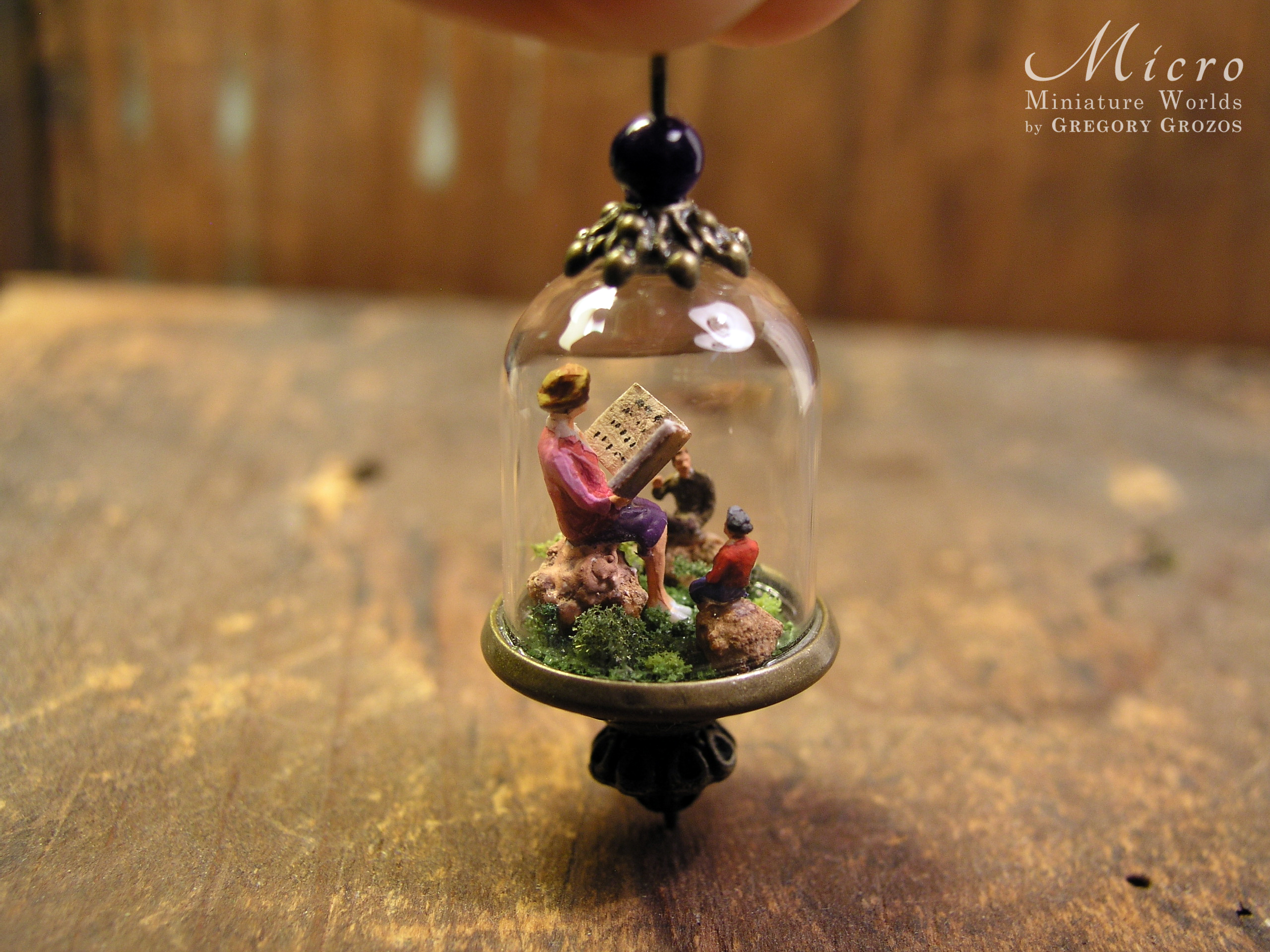 Miniature World pendant. A giant woman is reading stories to two tiny people