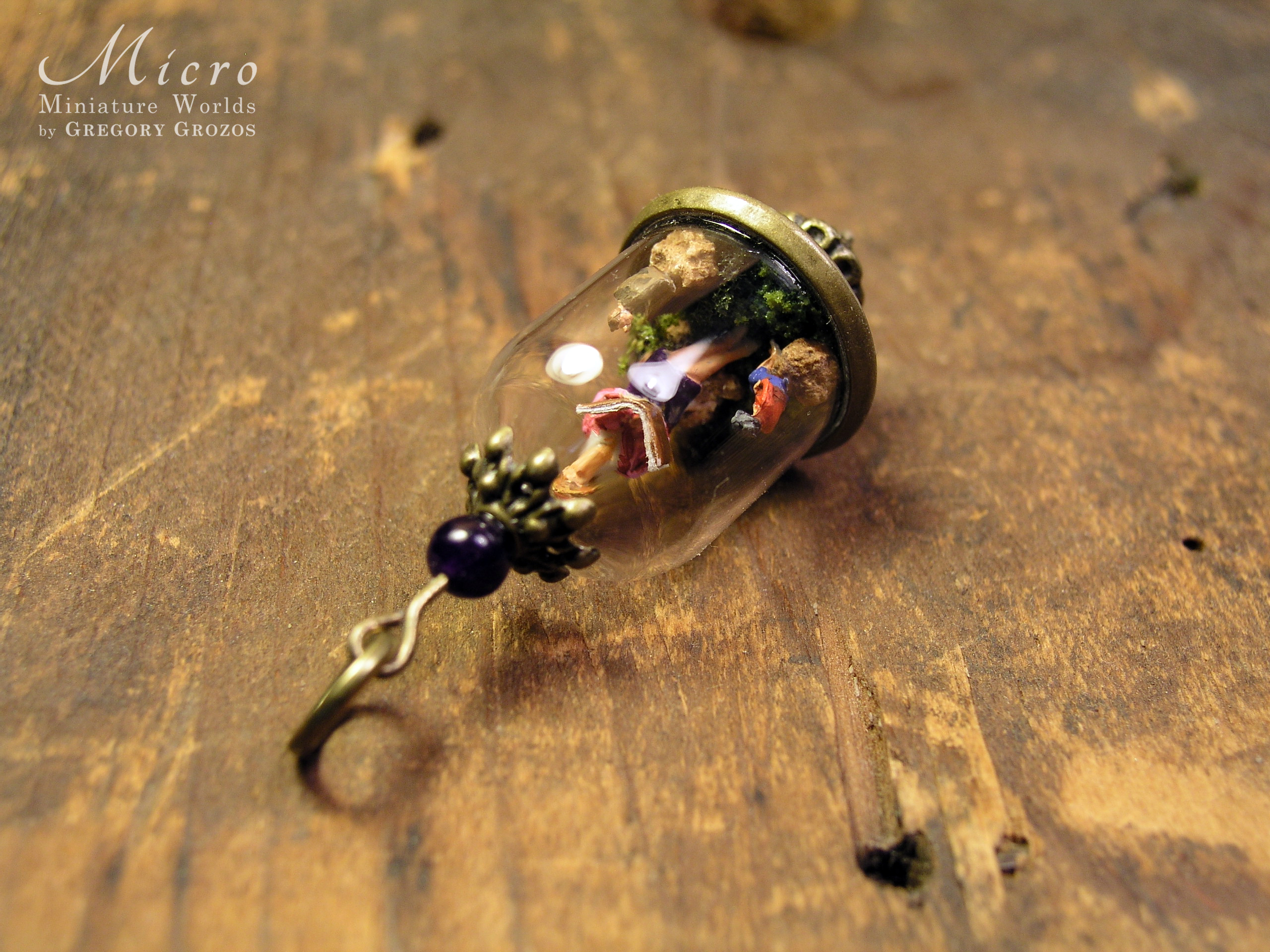 Miniature World pendant. A giant woman is reading stories to two tiny people