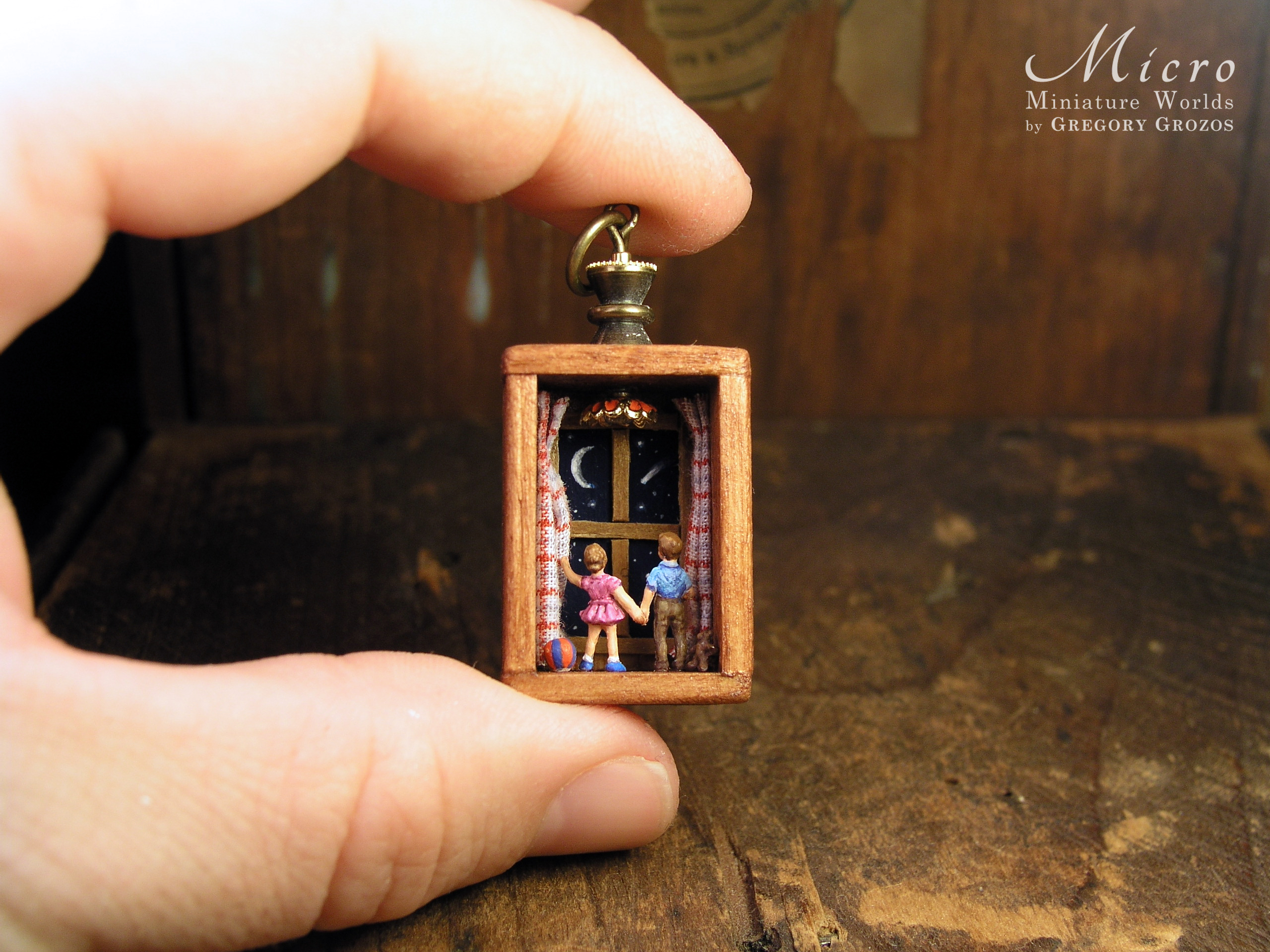 Miniature World Pendant. A boy and birl are holding hands while looking out a window at the night sky.