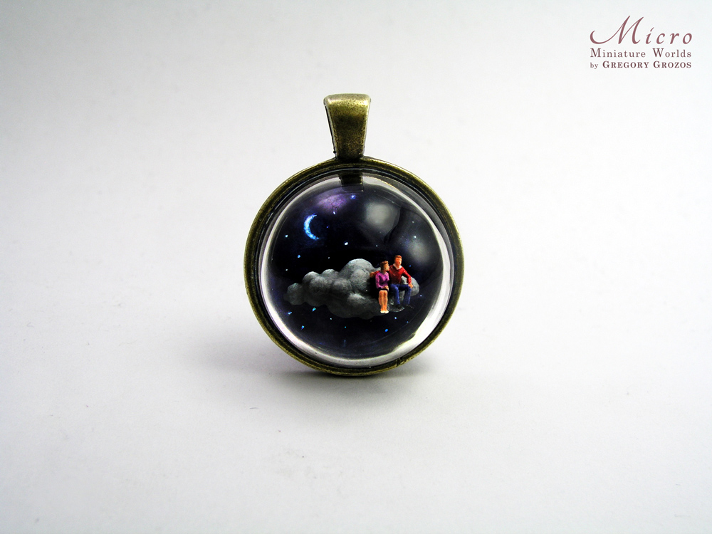 Miniature World pendant. A miniature man and woman are sitting on a cloud travelling through the night sky