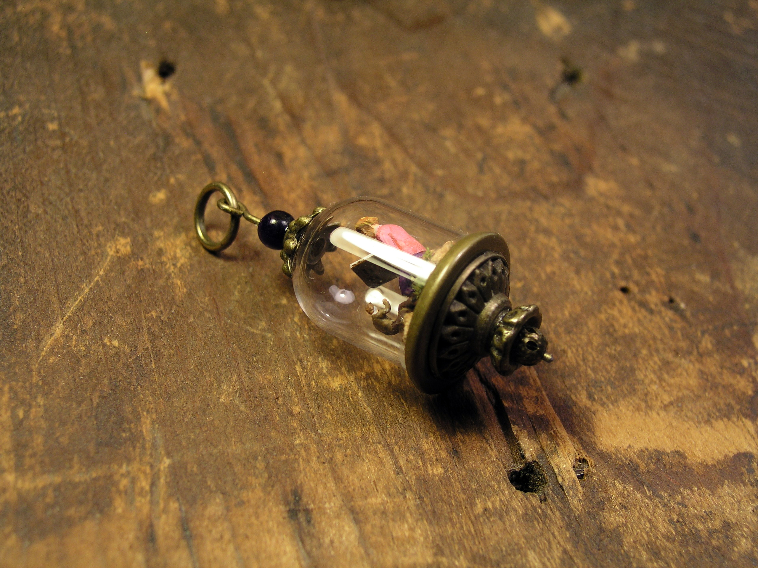 Miniature World pendant. A giant woman is reading stories to two tiny people