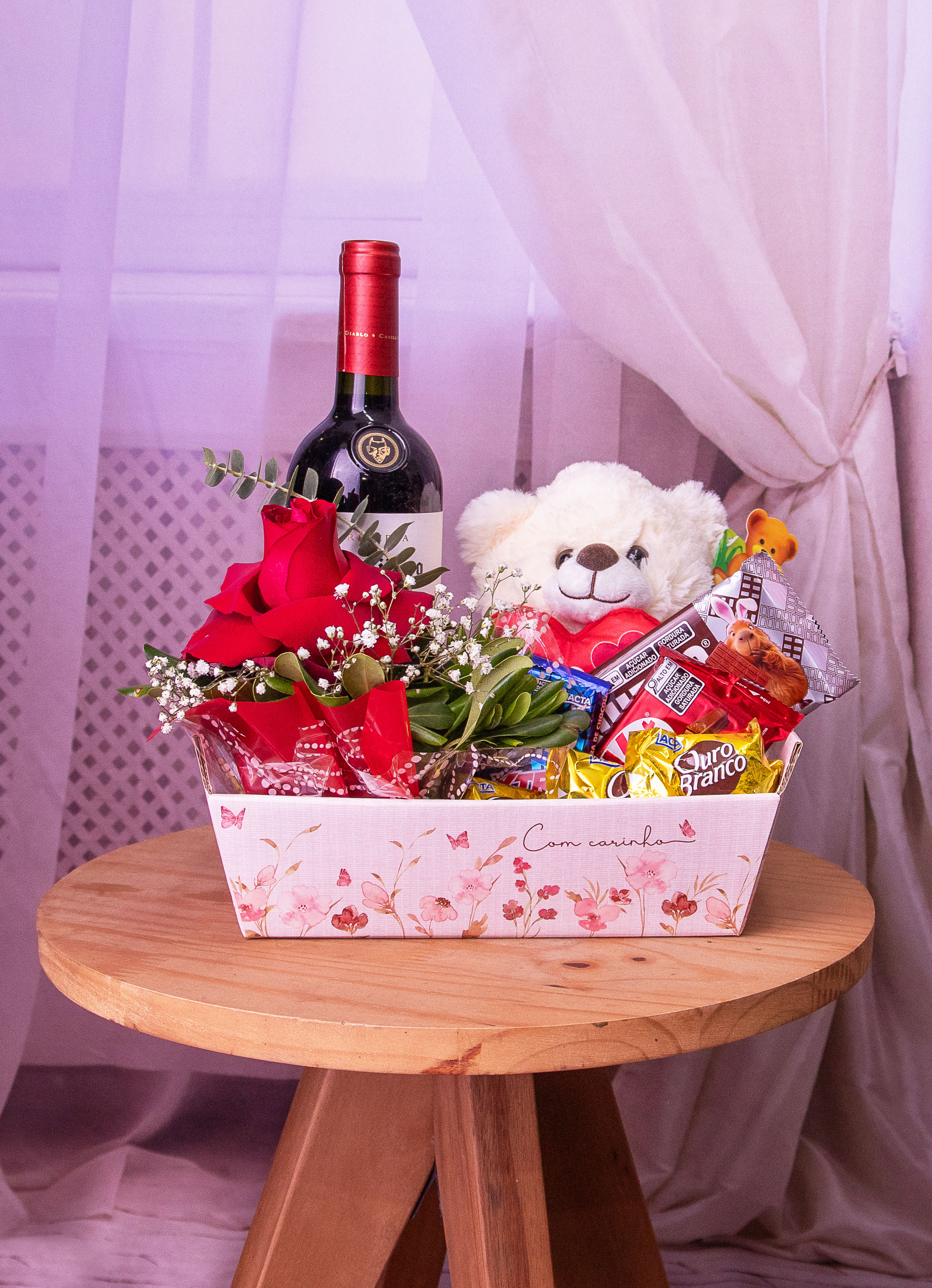 Cesta com Vinho, Chocolates, Urso e Arranjo com uma Rosa Vermelha.
