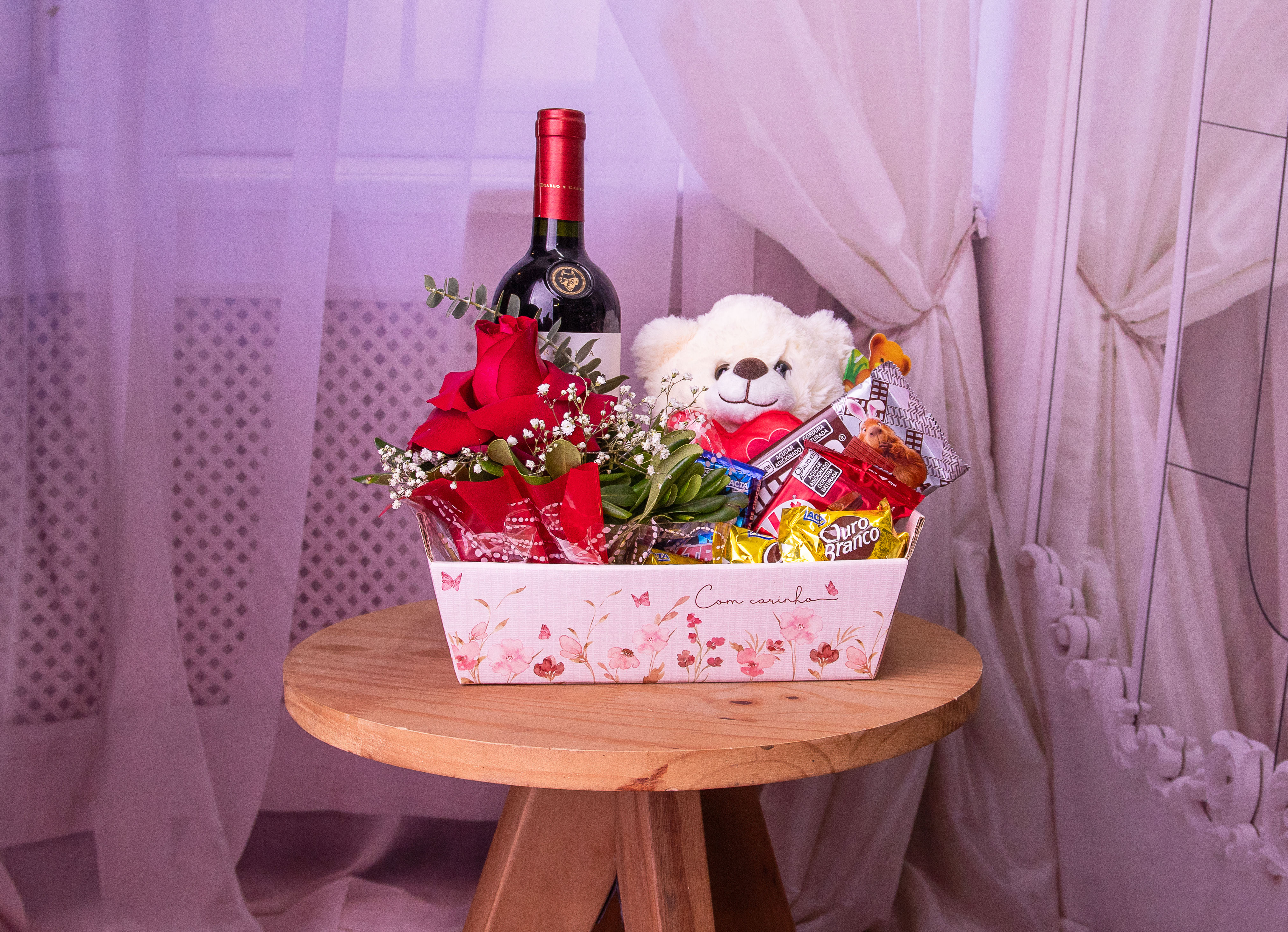 Cesta com Vinho, Chocolates, Urso e Arranjo com uma Rosa Vermelha.
