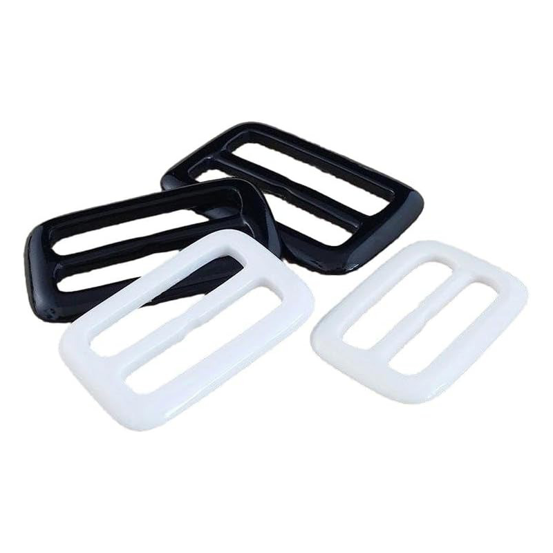 This white and black resin buckle is commonly used as an adjuster for backpack straps or belts.